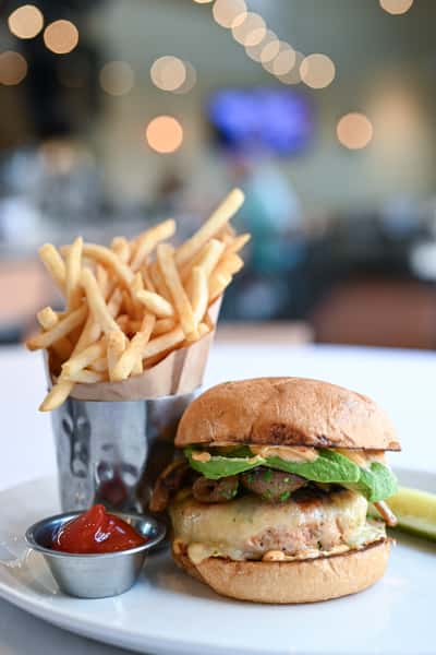 Salmon burger with fresh toppings and a side of crispy fries at Novara restaurant in Milton