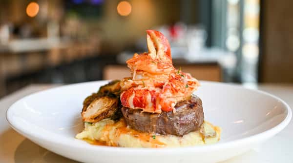 Surf and turf entrée with grilled filet steak, lobster tail, and creamy accompaniments at Novara in Milton