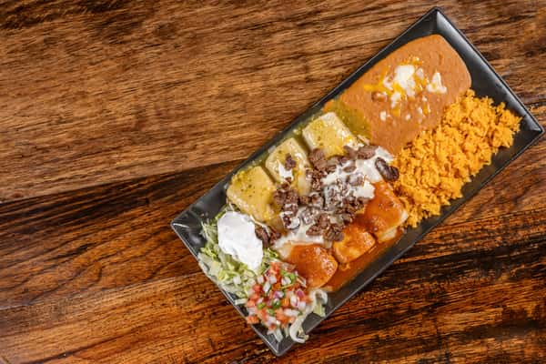 Colorful Mexican entrée with beef enchiladas topped with red and green sauce, melted cheese, sour cream, pico de gallo, refried beans, and seasoned rice.