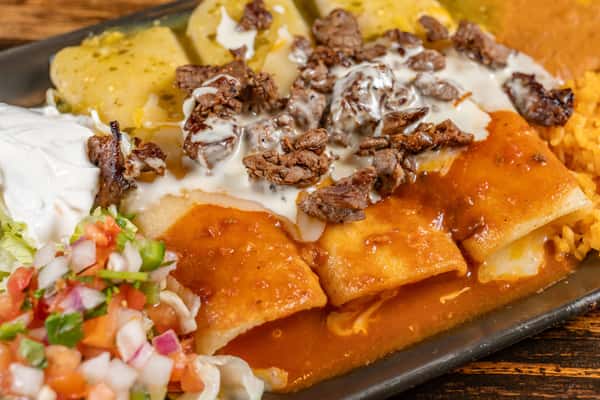 Cheese enchiladas topped with grilled carne asada and white queso sauce, served with green chile potatoes, Mexican rice, refried beans, pico de gallo, and sour cream.