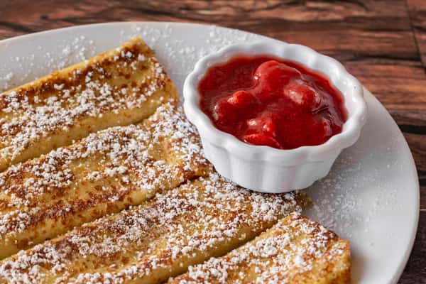 Golden-brown French toast sticks dusted with powdered sugar, served with a ramekin of sweet strawberry compote — a classic and kid-friendly breakfast dish.