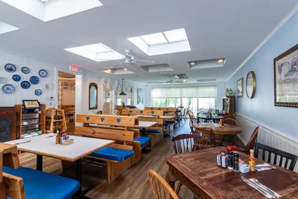 Bright and inviting dining area with natural skylights, wooden booths with blue cushions, and charming decor — a cozy, casual spot perfect for breakfast or lunch gatherings.