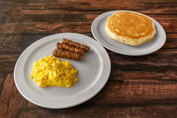 Classic American breakfast featuring fluffy scrambled eggs, sausage links, and a separate plate of golden pancakes — a hearty and satisfying morning meal.