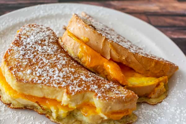 Thick slices of stuffed French toast dusted with powdered sugar and filled with melted cheddar and egg — a savory twist on a breakfast classic, perfect for morning comfort food.