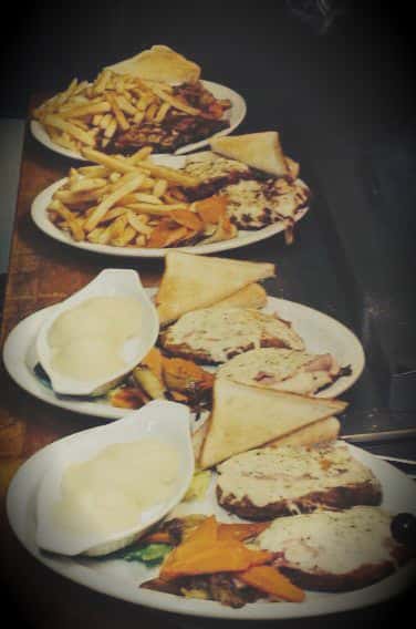 4 plates of food with sandwiches and fries