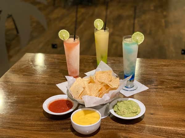 three frozen cocktails with chips, salsa, queso, and guac