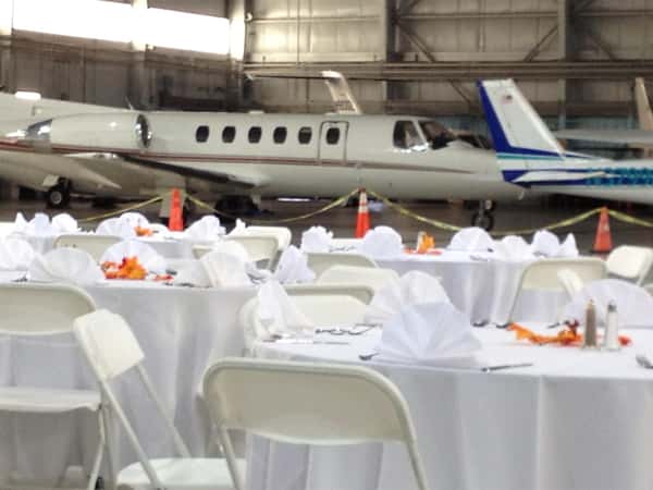 banquet tables set in an airplane hander with airplane in the background