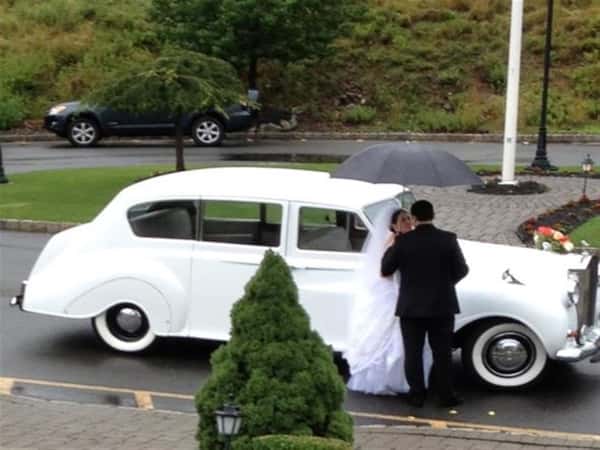 bride and groom kissing in front of a white car