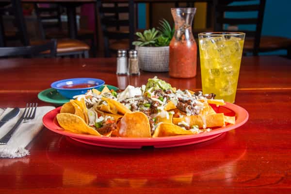 Loaded nachos topped with beans, cheese and jalapenos on a red plate