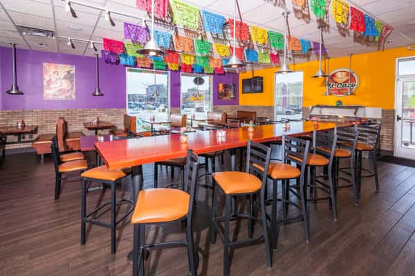 Colorful El Cazo dining room with orange chairs and papel picado banners