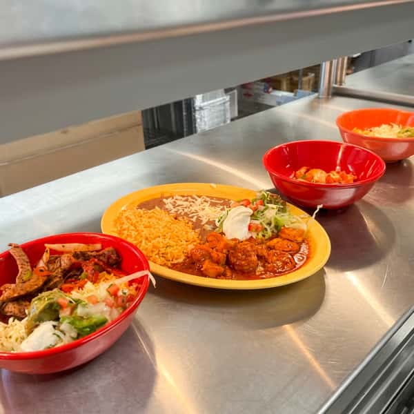 Fresh Mexican entrées prepared at El Cazo Mexican Restaurant featuring fajitas, spicy shrimp, and signature dishes ready to be served from the kitchen.