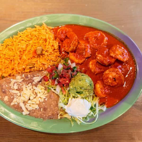 Camarones a la Diabla featuring spicy shrimp in a bold red chile sauce, served with Mexican rice, refried beans topped with melted cheese, guacamole, sour cream, and fresh pico de gallo at El Cazo Mexican Restaurant.