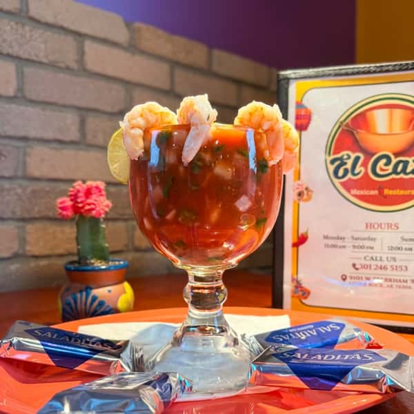 Mexican shrimp cocktail served with fresh shrimp, tomato, cilantro, onion, and lime in a chilled goblet at El Cazo Mexican Restaurant.