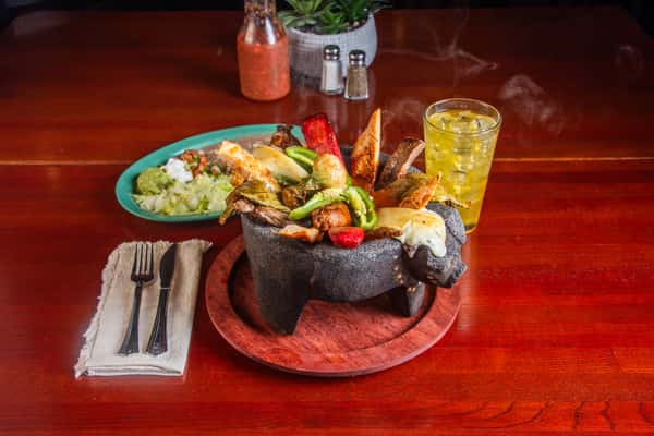 Molcajete El Cazo served in a stone bowl with grilled meats and vegetables