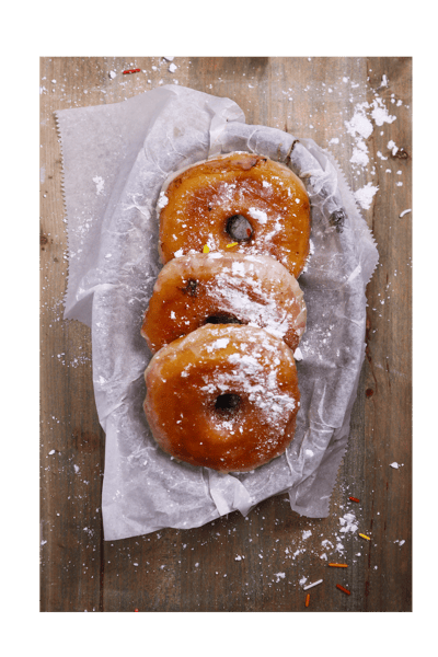 Hangry's Grill's three glazed donuts dusted with powdered sugar rest in a paper liner.