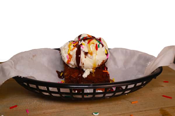 Hangry's Grill's brownie topped with ice cream and chocolate sauce sits in a black wire basket.