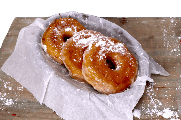 Hangry's Grill's Three glazed donuts, dusted with powdered sugar, sit in a paper-lined basket.