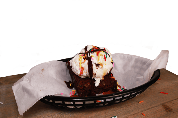 Hangry's Grill's warm brownie topped with vanilla ice cream, chocolate sauce, and sprinkles sits in a black basket lined with parchment paper.