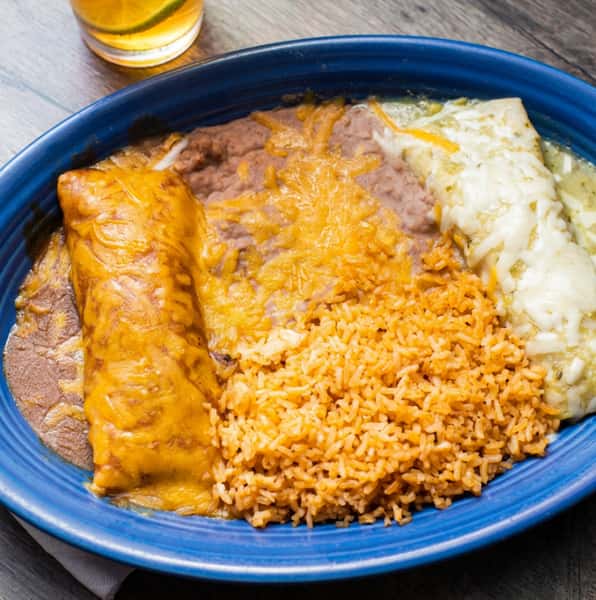 Enchilada platter with a cheese enchilada, a green chile enchilada, refried beans, and Spanish rice on a blue plate.