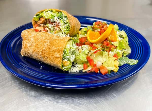 Chicken Caesar wrap, cut in half, with a side salad topped with pico de gallo and an orange slice on a blue plate.