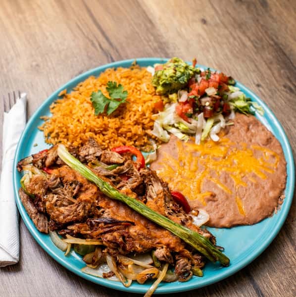 Fajita plate with beef, sautéed onions and peppers, rice, refried beans with cheese, guacamole, and salsa.
