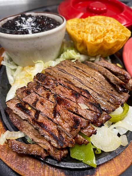 Sizzling steak fajitas with grilled peppers and onions, black beans, and a crispy tortilla bowl.