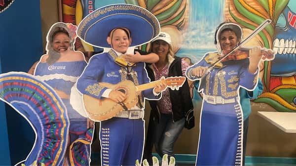 People standing behind cardboard cut outs of a mariachi band