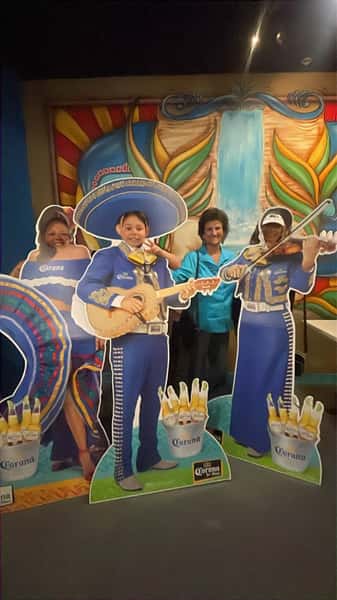 People standing behind cardboard cut outs of a mariachi band