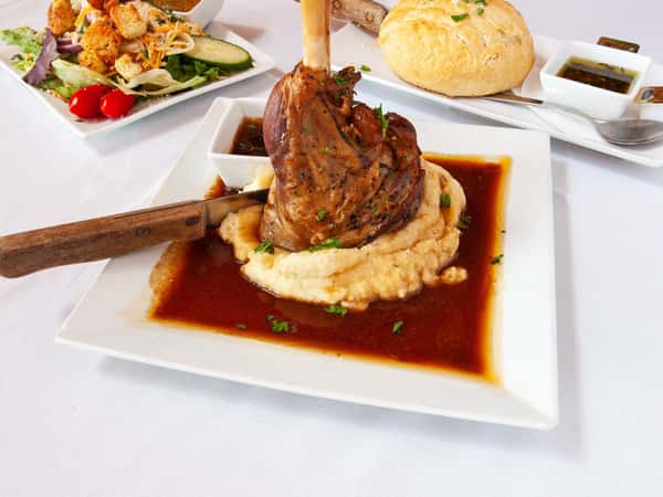 grilled lamb chop on a bed of mashed potatoes with a side of dipping sauce