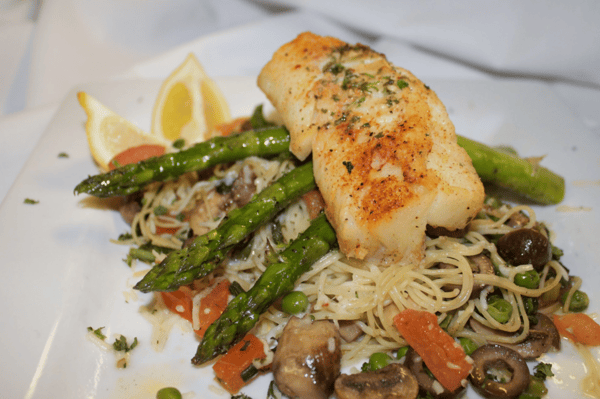 grilled salmon over a bed of spaghetti with vegetables and asparagus