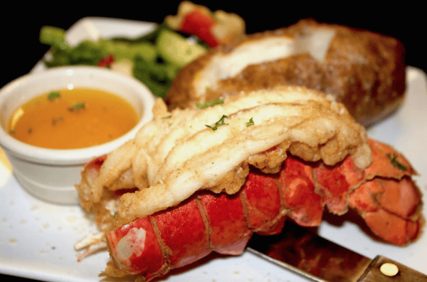 lobstger tail with a baked potato, side of vegetables, and butter