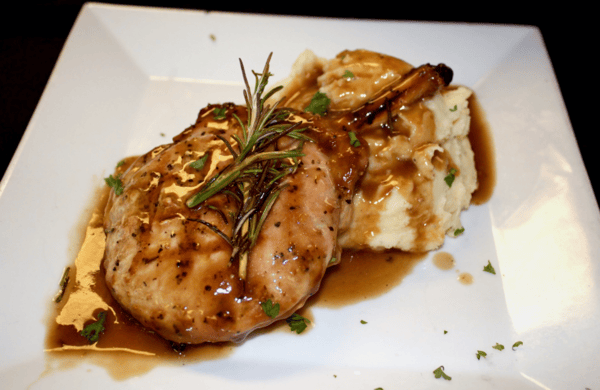 grilled chicken over mashed potatoes topped with sauce and garnish