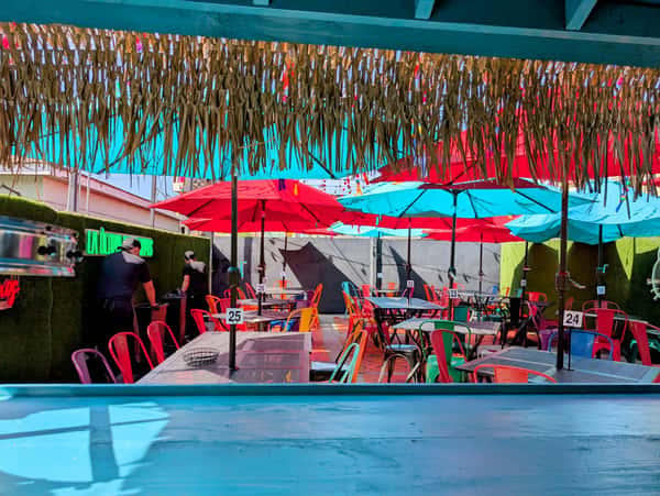 Vibrant outdoor patio dining showcases red and blue umbrellas shading tables