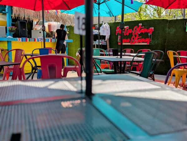 A close-up of a vibrant outdoor space showcases red and blue umbrellas shading tables