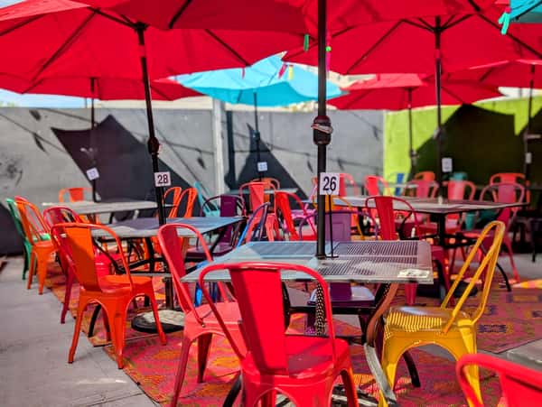Colorful chairs and tables sit under bright umbrellas