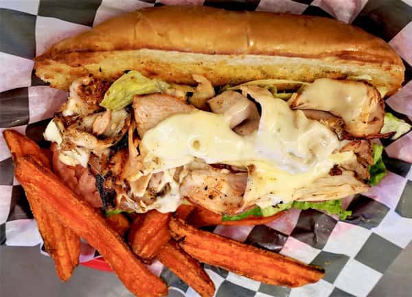 grilled chicken sandwich with lettice and tomatoes. Topped with cheese and a side of sweet potato fries