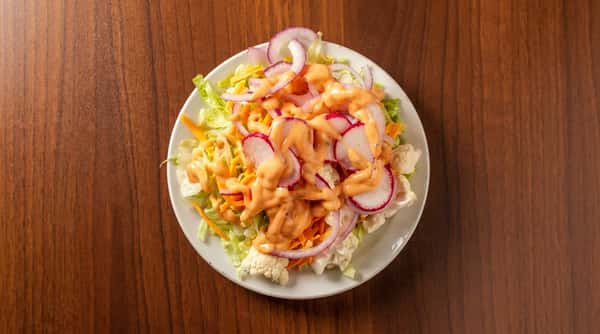 Garden salad with shredded lettuce, carrots, cheese, sliced radish, red onion, and creamy orange dressing.