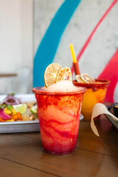 Vibrant red frozen cocktail with dried lime and chili-salt rim, served with tacos at Milagro Tacos Cantina.