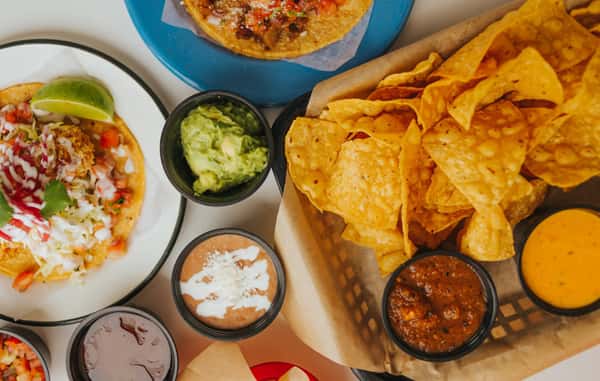 Milagro Tacos Cantina's vibrant Mexican feast with loaded tacos, golden tortilla chips, fresh guacamole, salsa, queso, and bean dips.