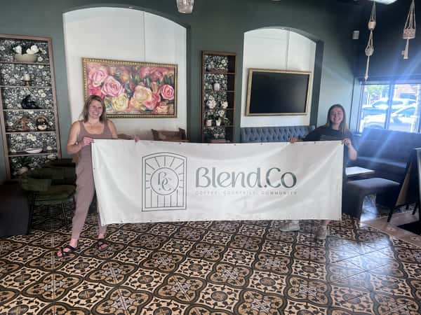 Owners Haley and Suzy hanging up the Blend.Co banner for the first time (Sept 2025)