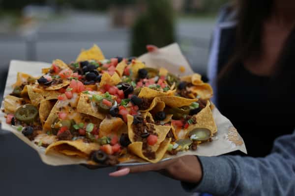 person holding plate of nachos