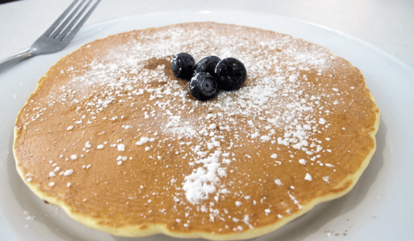 pancakes dusted with powdered sugar and blueberries in the center