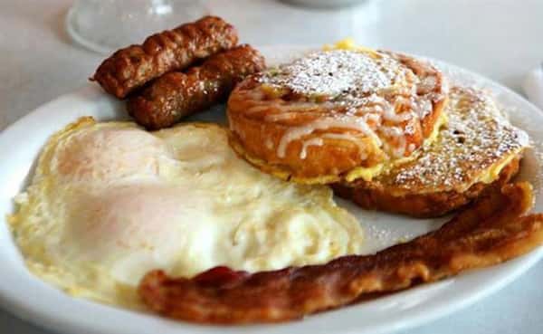 challah bread French Toast served with two eggs any style and two strips of bacon or two sausage links