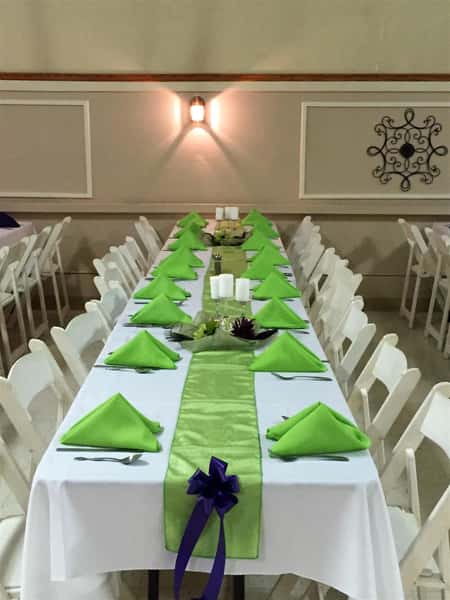 long table setup with tablecloths, folded napkins and ribbon decorations with candles