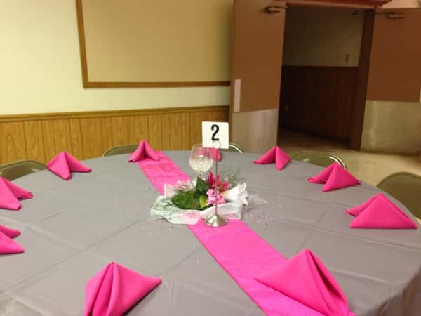 circular table with a tablecloth, folded napkins and a floral centerpiece