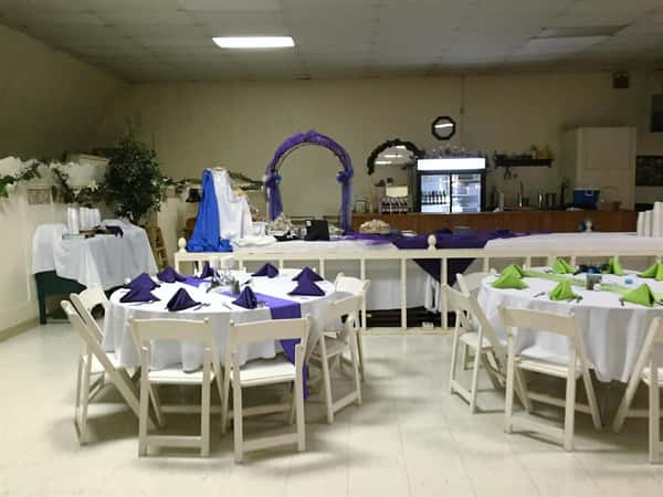 set of circular tables setup with tablecloths, folded napkins and ribbon decorations
