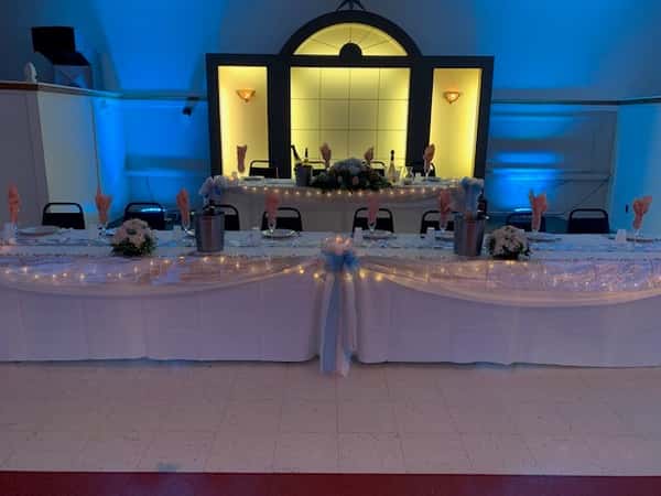 set of tables with a tablecloth, folded napkins and candles as centerpieces