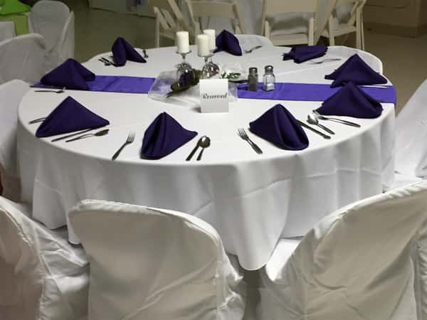 circular table with a tablecloth, folded napkins and candles as centerpieces