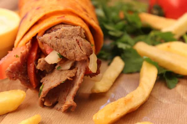 -tasty-doner-kebab-roll-with-french-fries-and-herbs-on-a-wood