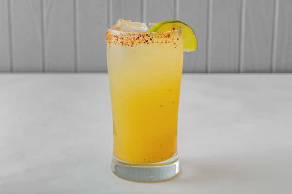 Refreshing citrus cocktail served over ice in a tall glass with a chili-lime Tajín rim and lime wedge garnish — a zesty and spicy drink perfect for summer sipping. Image 2 (Chicken Parmesan Sandwich with Tater Tots – Top View)
